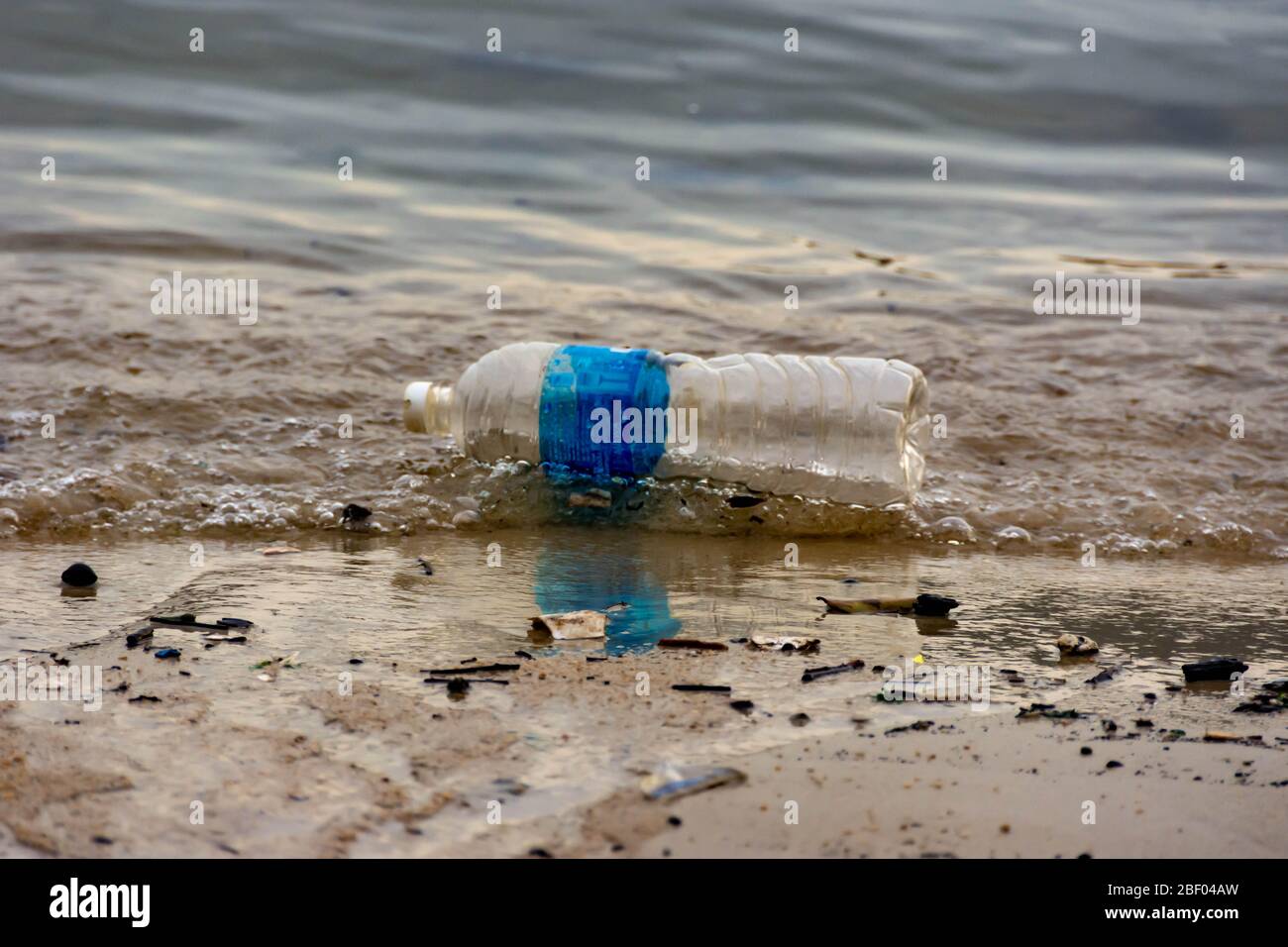 Rifiuti di plastica della bottiglia d'acqua su una baia che inquina l'oceano. Rifiuti di plastica gettati dalla spiaggia Foto Stock