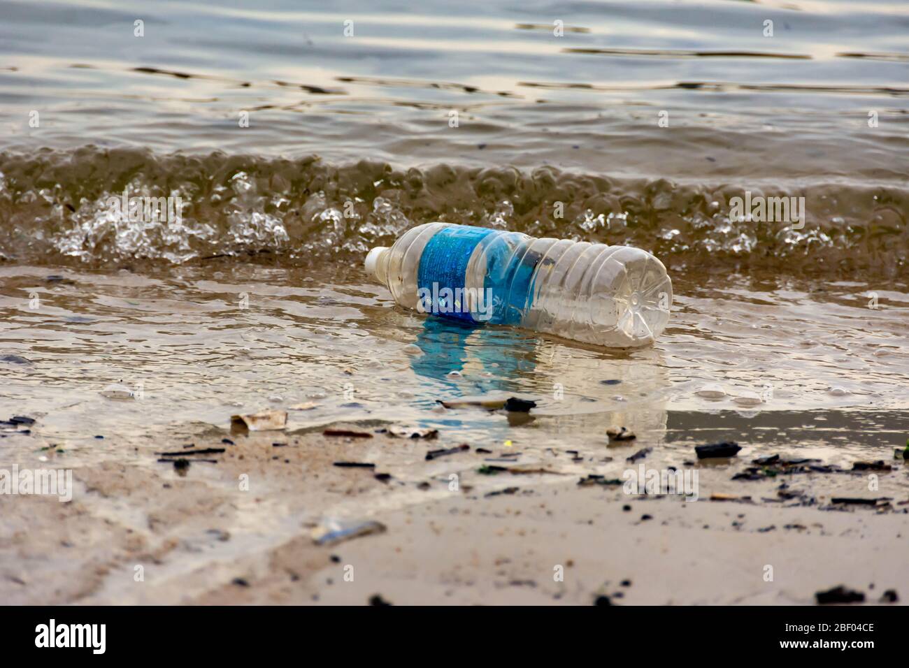 Rifiuti di plastica della bottiglia d'acqua su una baia che inquina l'oceano. Rifiuti di plastica gettati dalla spiaggia Foto Stock