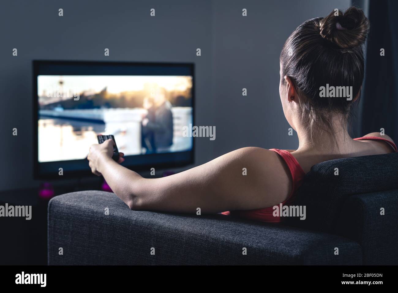 Donna che guarda film o serie. Persona che utilizza il telecomando Smart tv per scegliere un film o cambiare canale. Streaming o video on demand (VOD). Foto Stock
