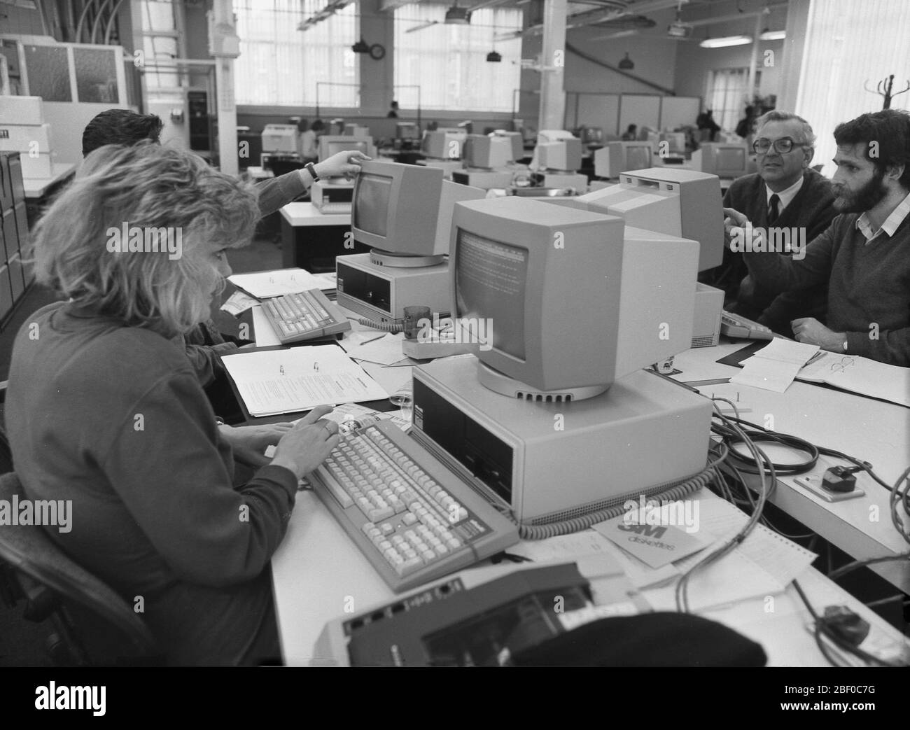 1987, giornalisti che utilizzano personal computer (PC) in un ufficio di giornali affollato. Gli editori di giornali sono stati uno dei primi a vedere l'enorme potenziale dei PC per rendere i loro metodi di lavoro più efficienti e convenienti, rispetto al vecchio metodo di composizione dei metalli ad alta intensità di lavoro. Foto Stock