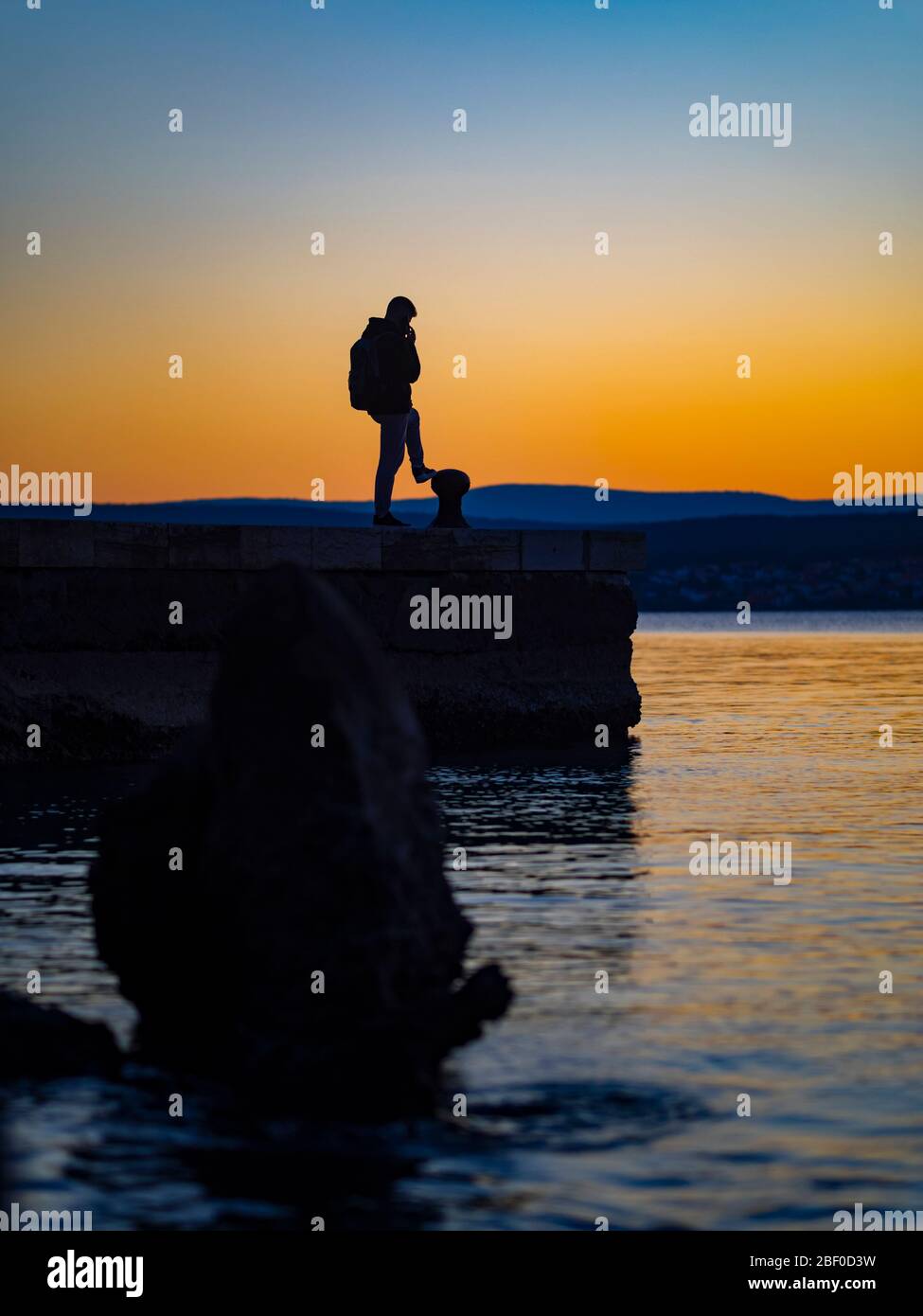 Tramonto silhouette uomo persona che parla sul mare utilizzando tenere cellulare cellulare cellulare cellulare Foto Stock