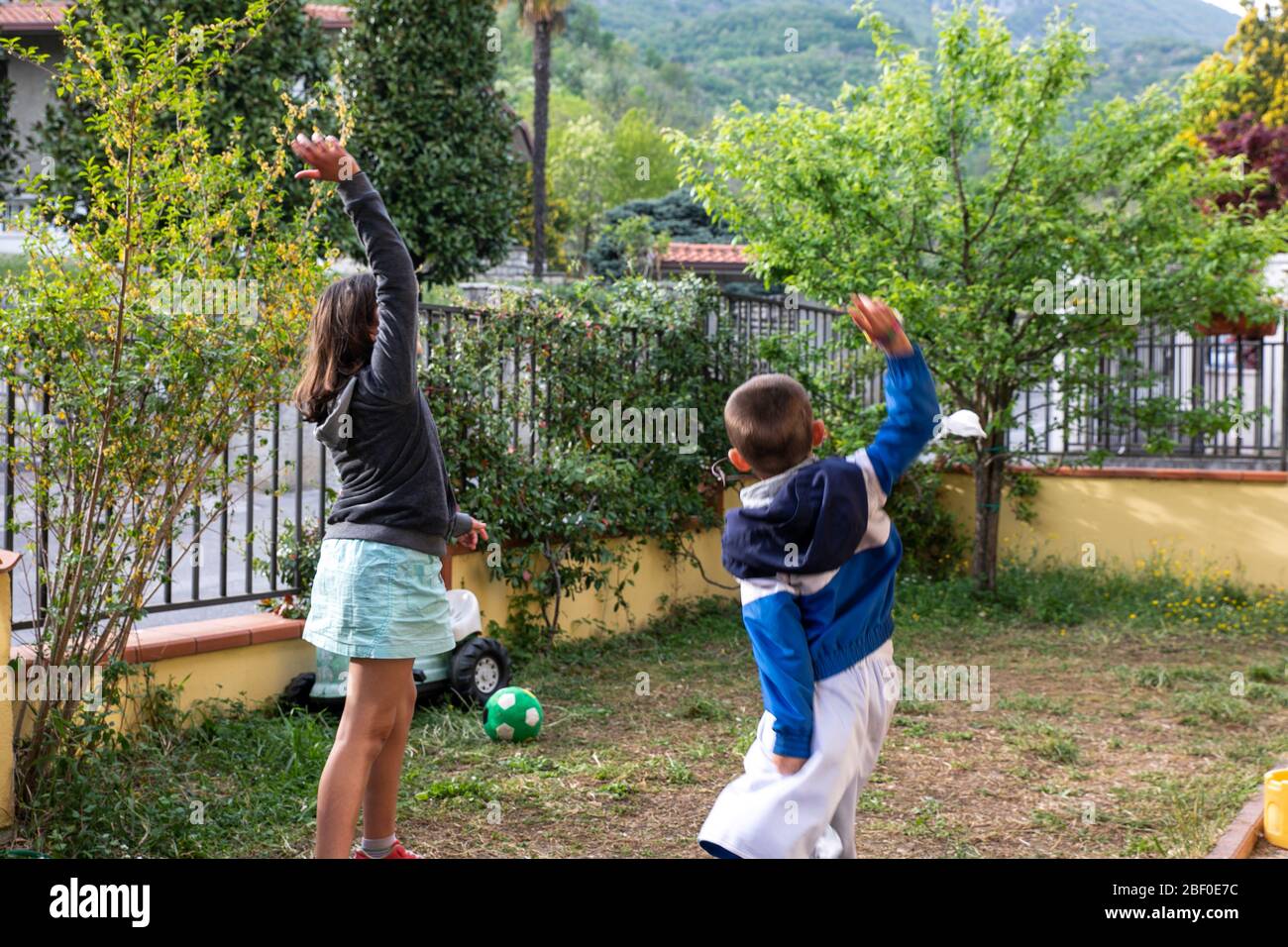 Ragazzo e ragazza togliere la maschera medica e andare a giocare in giardino, dopo la quarantena coronavirus Foto Stock