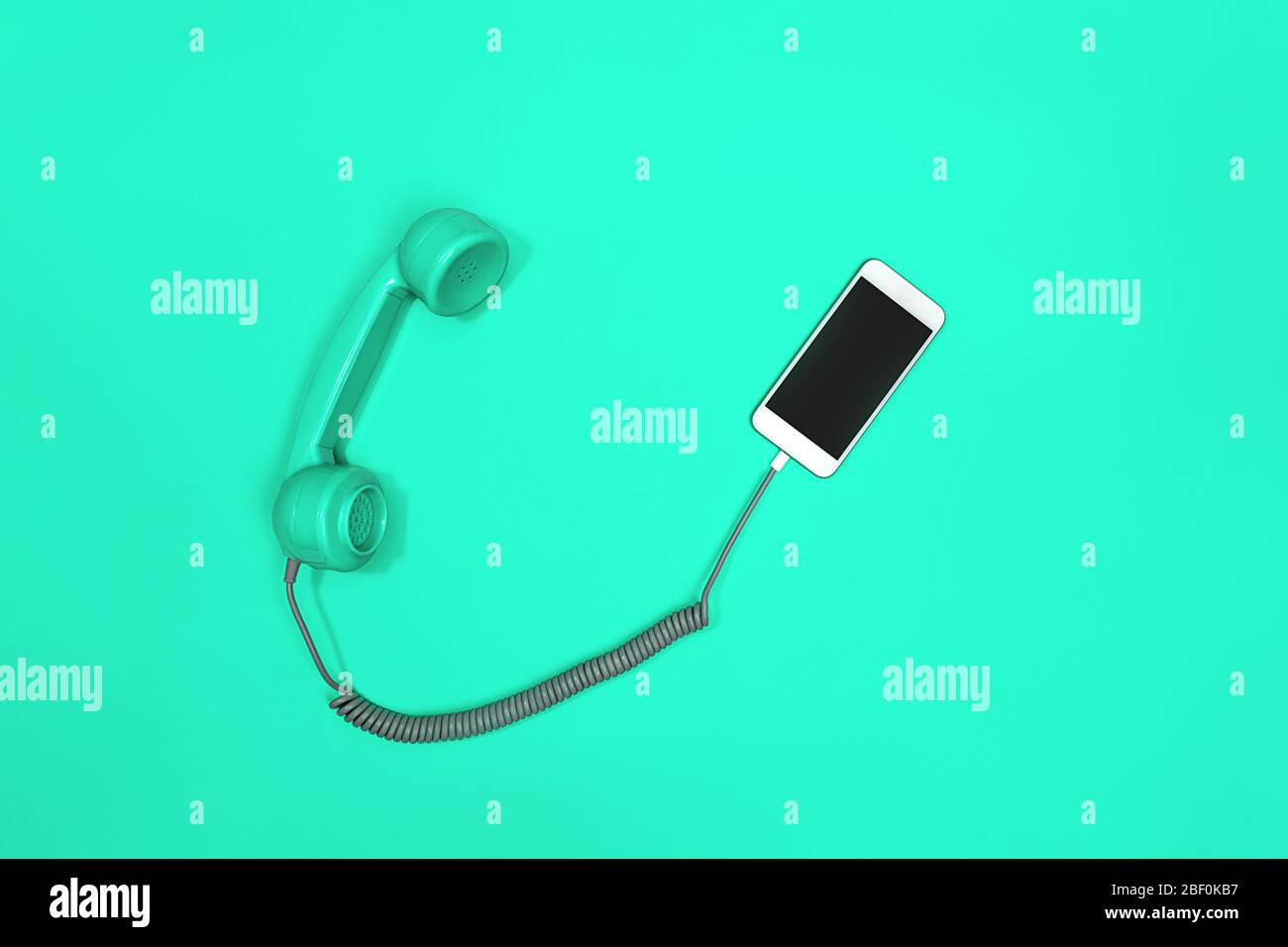 Telefono cellulare e vecchio stile su sfondo verde menta neo. Stile moderno retro. Nuova vecchia tecnologia. Foto Stock