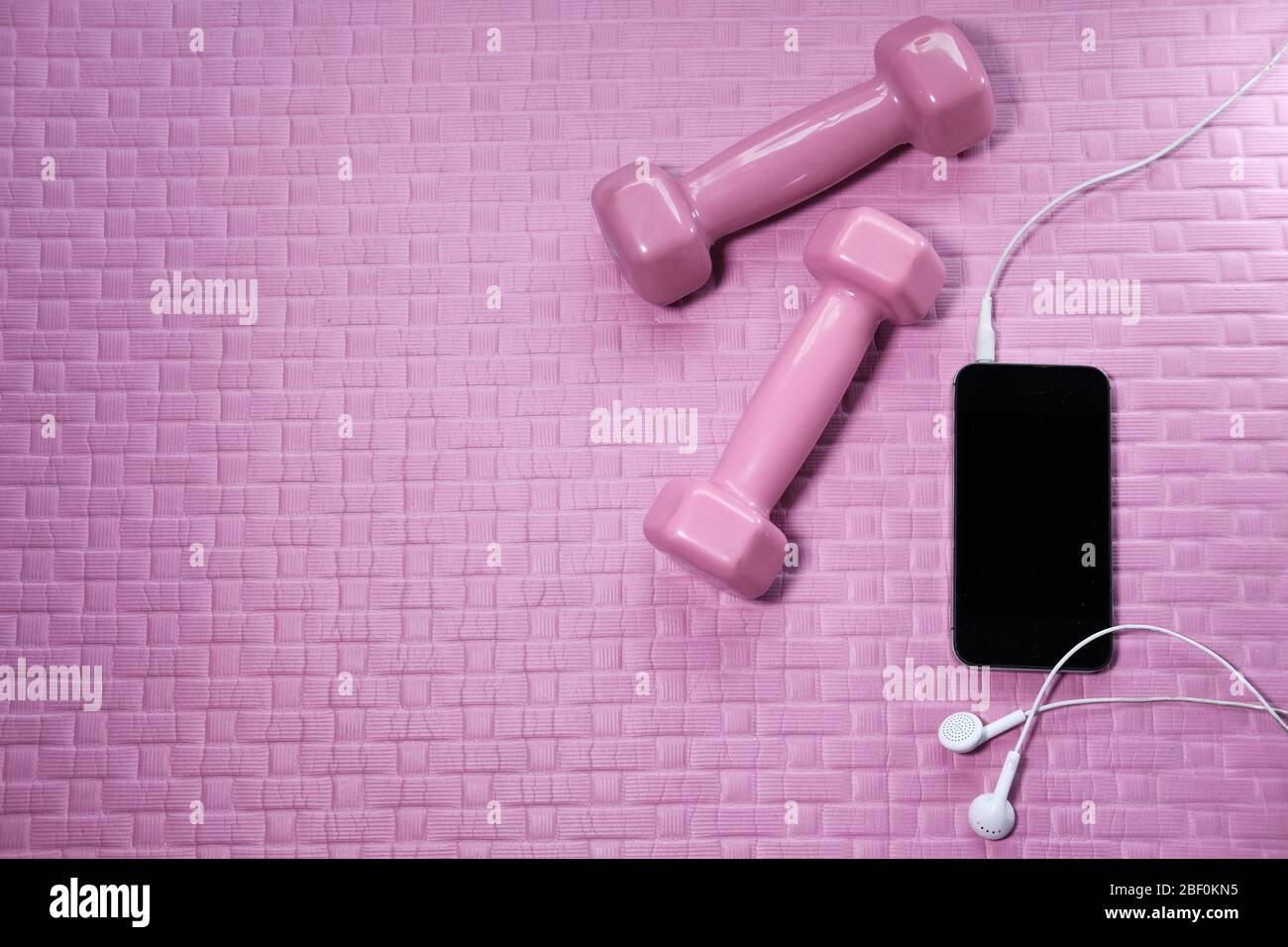 telefono mart e manubri sul tappetino per esercizi Foto Stock