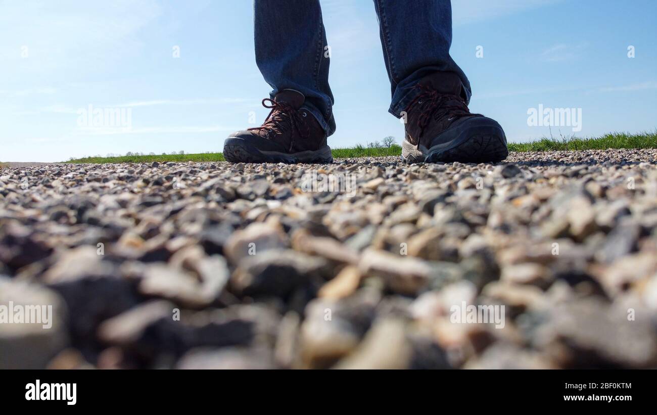 Le gambe di un uomo in sneakers si trovano su una strada di ghiaia Foto Stock