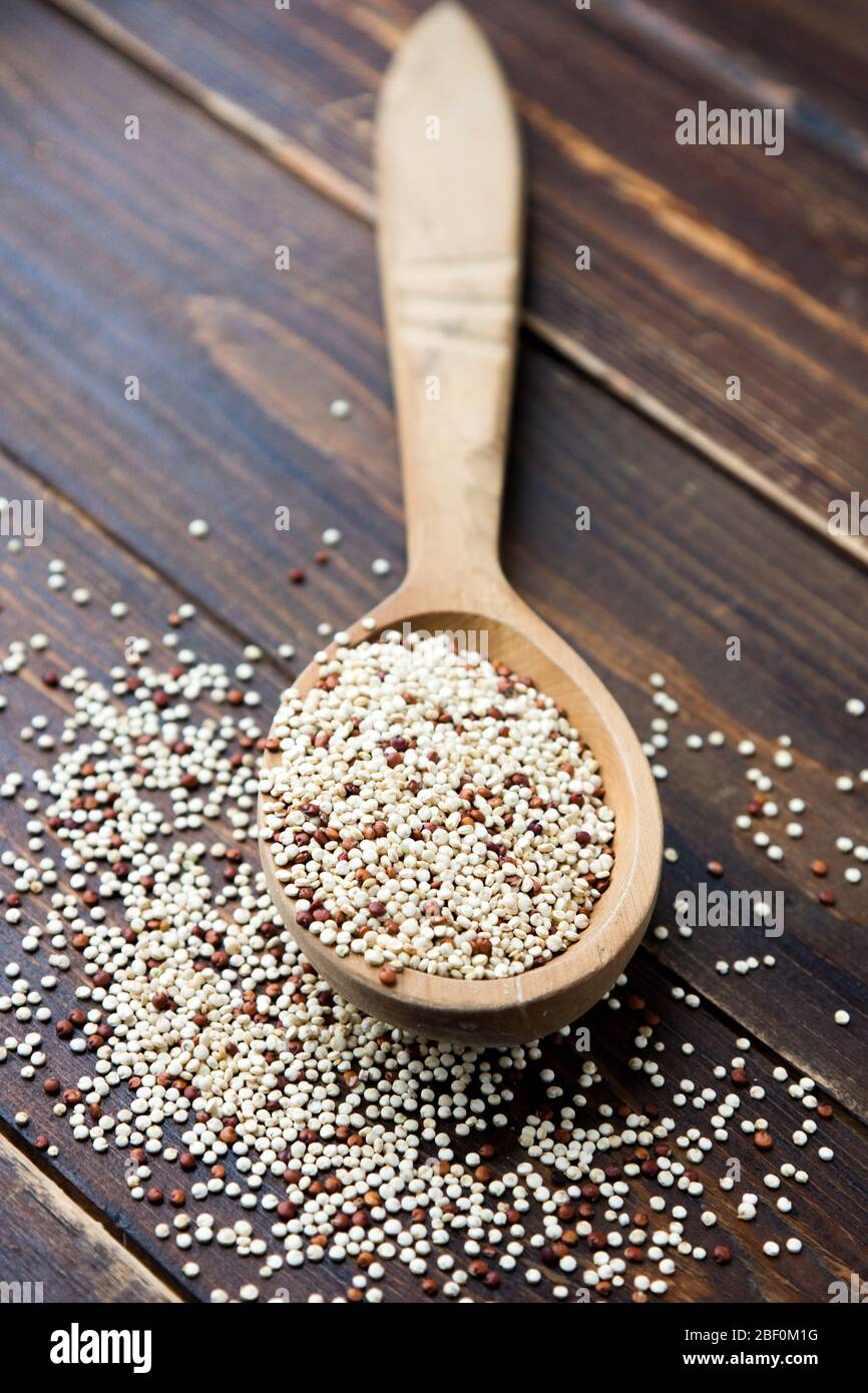 Chicchi di quinoa biologica in cucchiaio di legno, senza glutine. Concetto di cibo sano. Dieta. Semi di Chenopodium quinoa Foto Stock