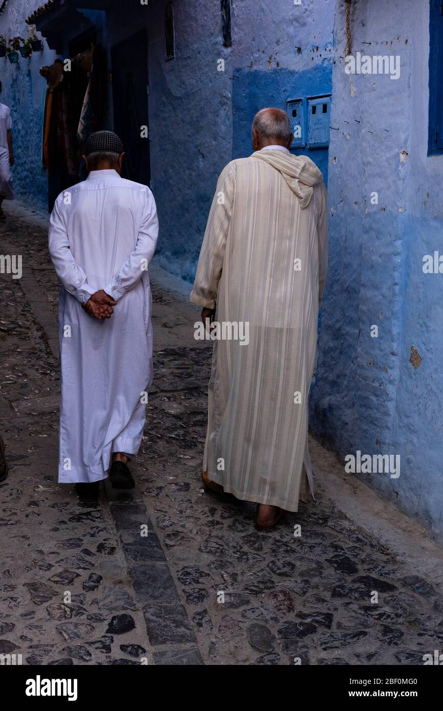 Chefchaouen, Marocco settentrionale, 10 giugno 2016. Due anziani, in tradizionale abito marocchino, camminano su una delle strade della città blu. Foto Stock