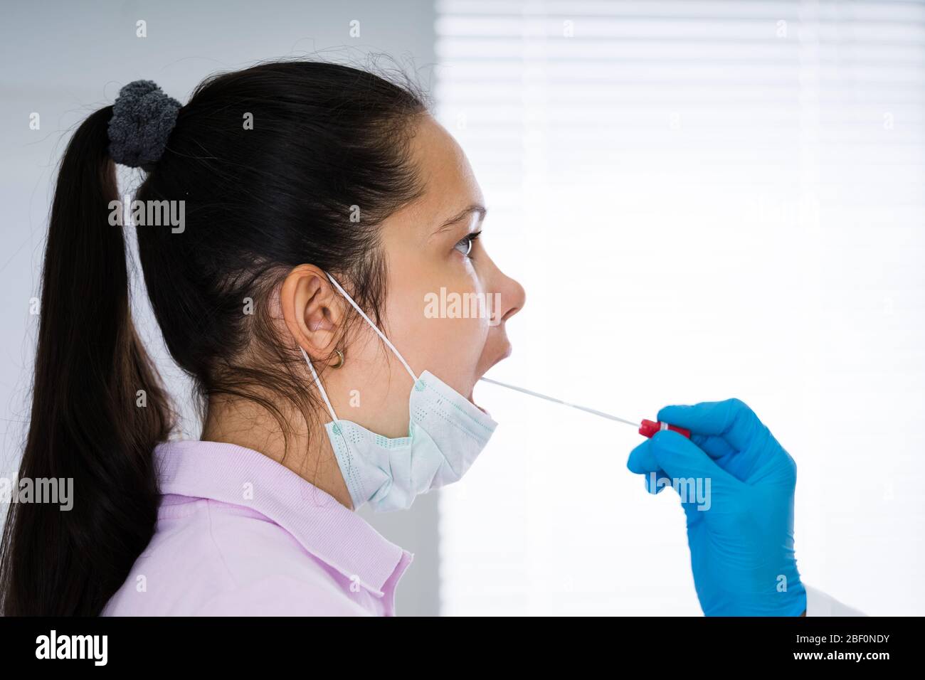 Medico che assume un campione di tampone liquido per bocca da Throat Foto Stock