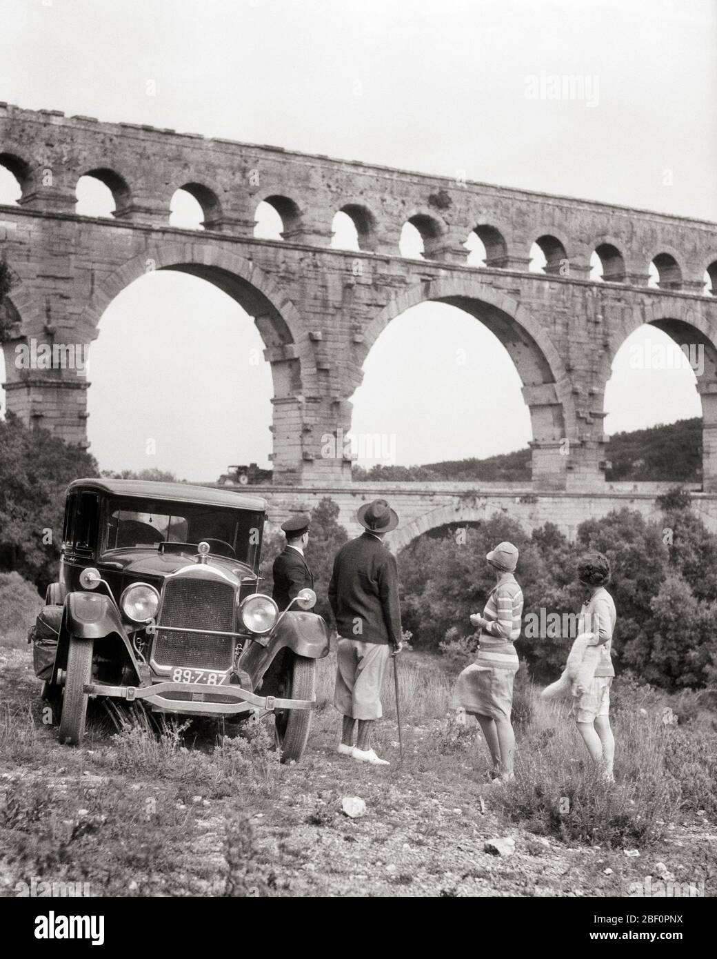 1920 GRUPPO TURISTICO IN PIEDI IN AUTO GUARDANDO L'ANTICO ACQUEDOTTO ROMANO PONTE PONT DU GARD COSTRUITO NEL 50 DC VICINO A NIMES FRANCIA - M1830 HAR001 HARS PERSONE ISPIRAZIONE PANORAMICA AUTOMOBILE MASCHI TRASPORTO EUROPA B&W ROMANA ANTICA STRUTTURA DU ALTA ANGOLO AVVENTURA AUTOS EUROPEO TURISMO VICINO AL MOVIMENTO BLUR AUTOMOBILI DI STILE VEICOLI GARD COSTRUITO CALCARE MEDIO-ADULTO UOMO MEDIO-ADULTO DONNA METÀ-ADULTO INSIEME ATTRAZIONE TURISTICA ARCHI BIANCO E NERO ETNIA CAUCASICA HAR001 VECCHIO STILE SITO PATRIMONIO MONDIALE DELL'UNESCO Foto Stock