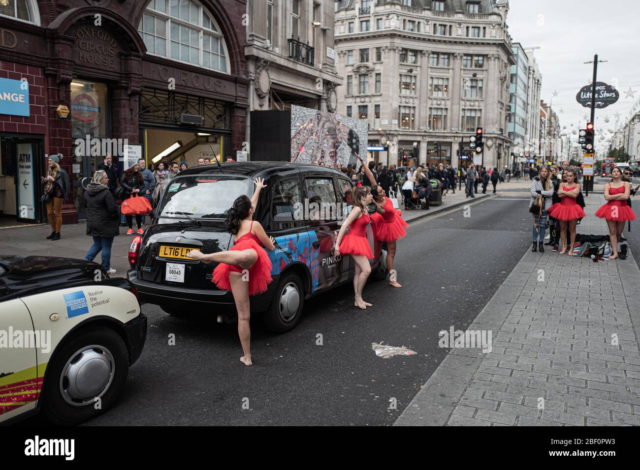 Ballerini classici vestiti in rosso che si esibiscono per strada a Londra, Regno Unito Foto Stock