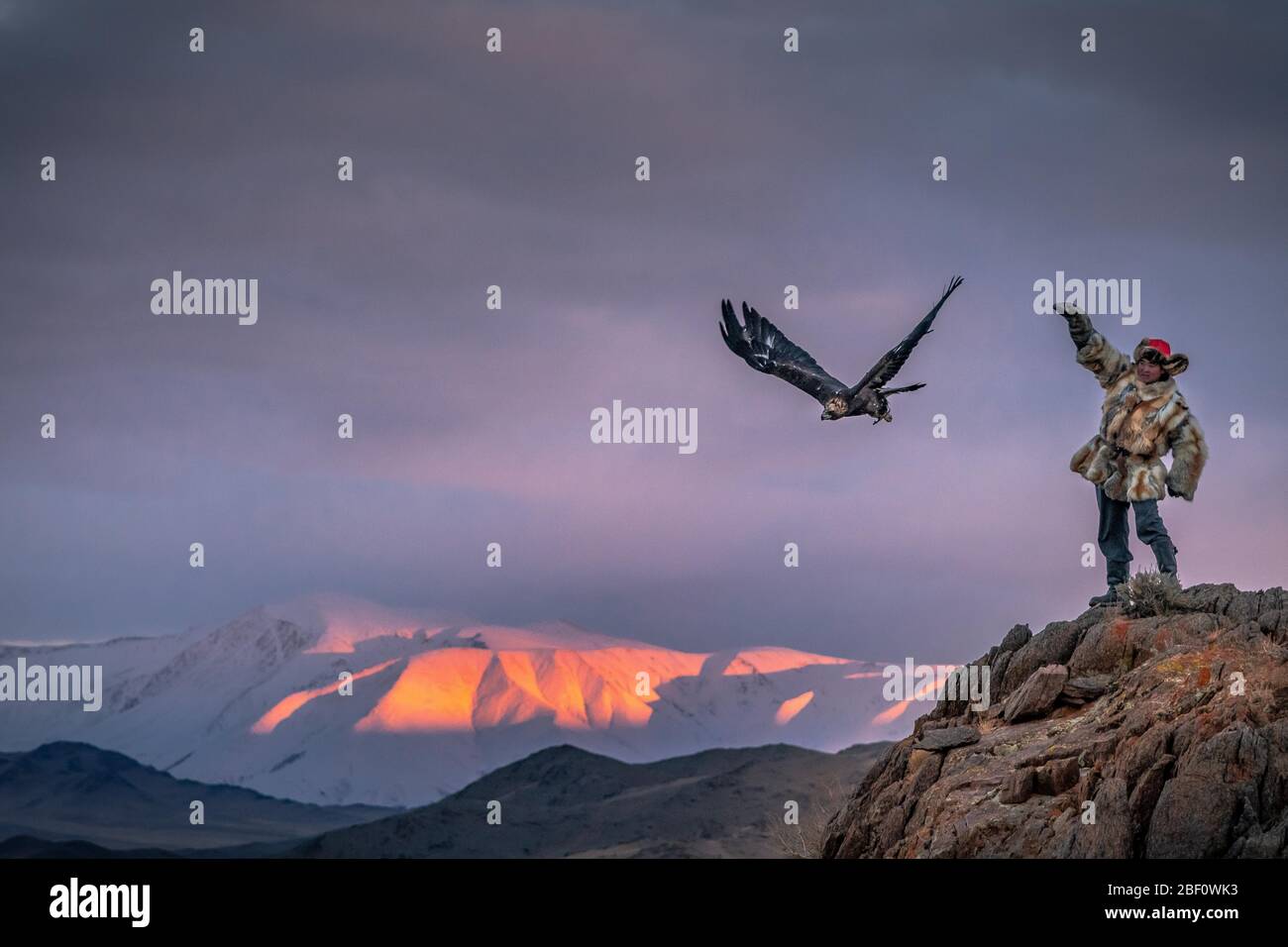 Cacciatore di aquile mongolo con aquila di lancio sulla roccia, provincia di Bajan-Oelgii-Aimag, Mongolia Foto Stock