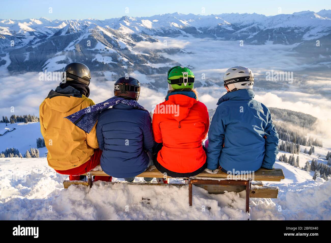 Sciatori seduti su una panchina e affacciati sulle montagne innevate, SkiWelt Wilder Kaiser Brixental, Brixen im Thale, Tirolo, Austria Foto Stock