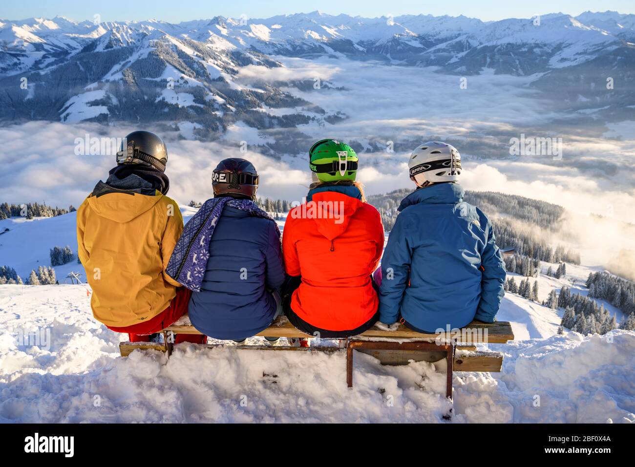 Sciatori seduti su una panchina e affacciati sulle montagne innevate, SkiWelt Wilder Kaiser Brixental, Brixen im Thale, Tirolo, Austria Foto Stock