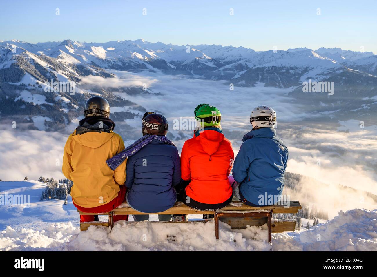 Sciatori seduti su una panchina e affacciati sulle montagne innevate, SkiWelt Wilder Kaiser Brixental, Brixen im Thale, Tirolo, Austria Foto Stock