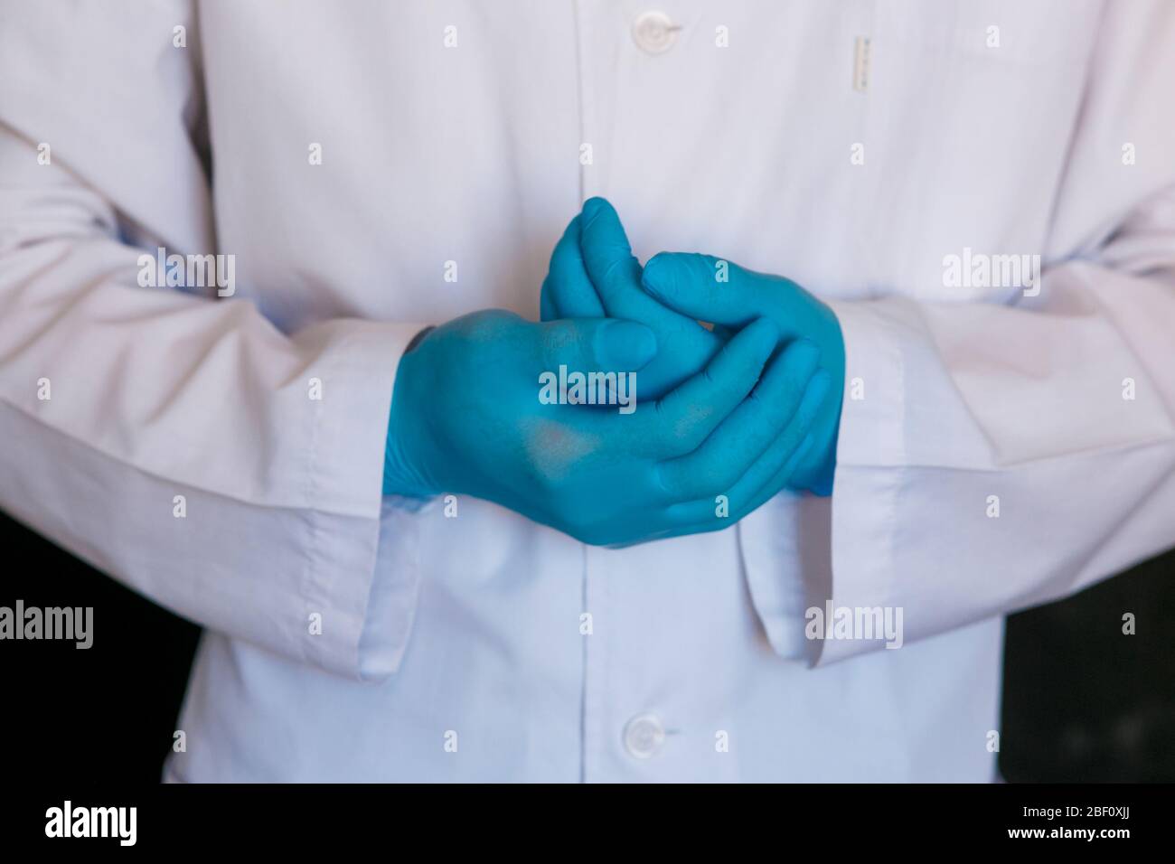 primo piano del medico. Guanti medici del chirurgo su sfondo nero. Foto Stock