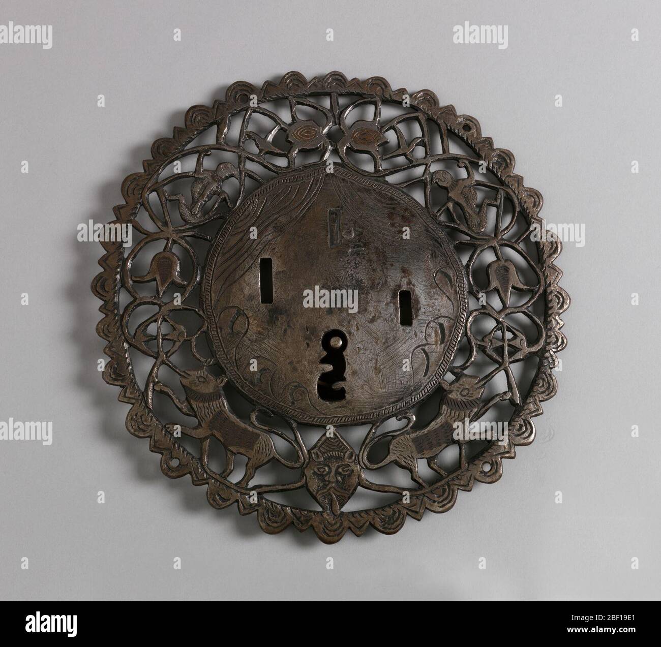 Blocco e chiave. Serratura circolare con bordo aperto raffigurante tulipani, leoni e possibilmente scimmie. Maschera in basso. Coppia con -134 Foto Stock