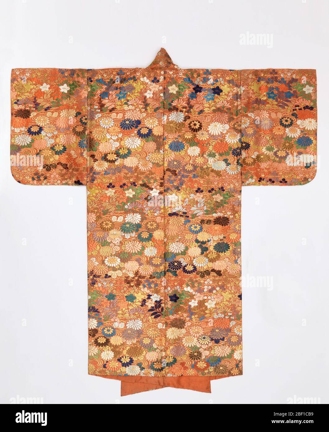 ROBE NOH. NOH tondino teatrale in terracotta di seta broccata pesantemente in seta colorata e carta dorata con un disegno di crisantemi e fiori a cinque petali. Foderato in seta di terracotta. Foto Stock