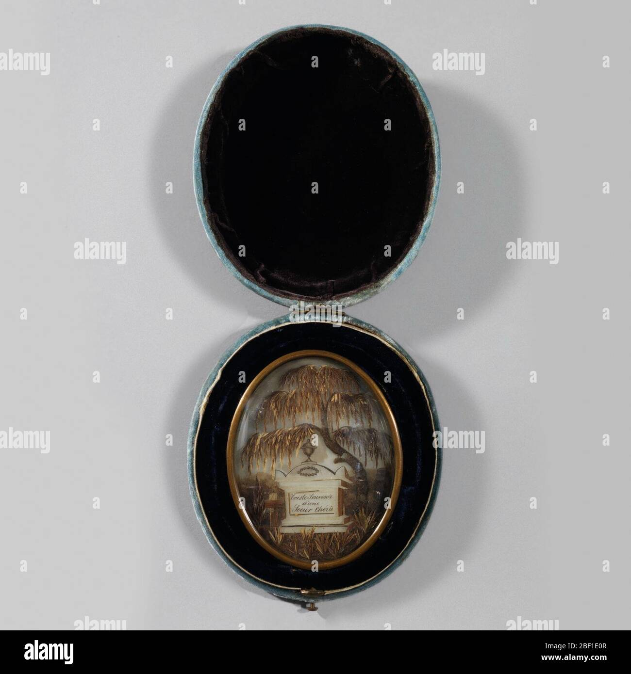 Immagine lutto. Forma ovale in ottone che circonda la scena fatta di capelli, raffigurante monumento tomba sormontata da urna e scritta: 'Triste souvenir d'une soeur cherie.' Tomba fiancheggiata da ciuffi di erba con un albero di salice piangente dietro, il tutto sotto una copertura di vetro a cupola. Foto Stock