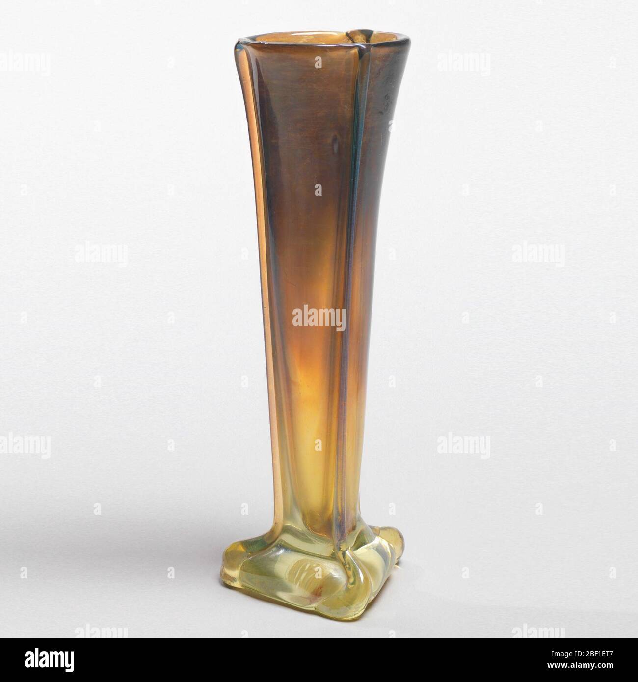 Vaso. Vaso di forma triangolare con tre lunghe nervature di vetro applicate; colore da giallo scuro a giallo chiaro. Foto Stock