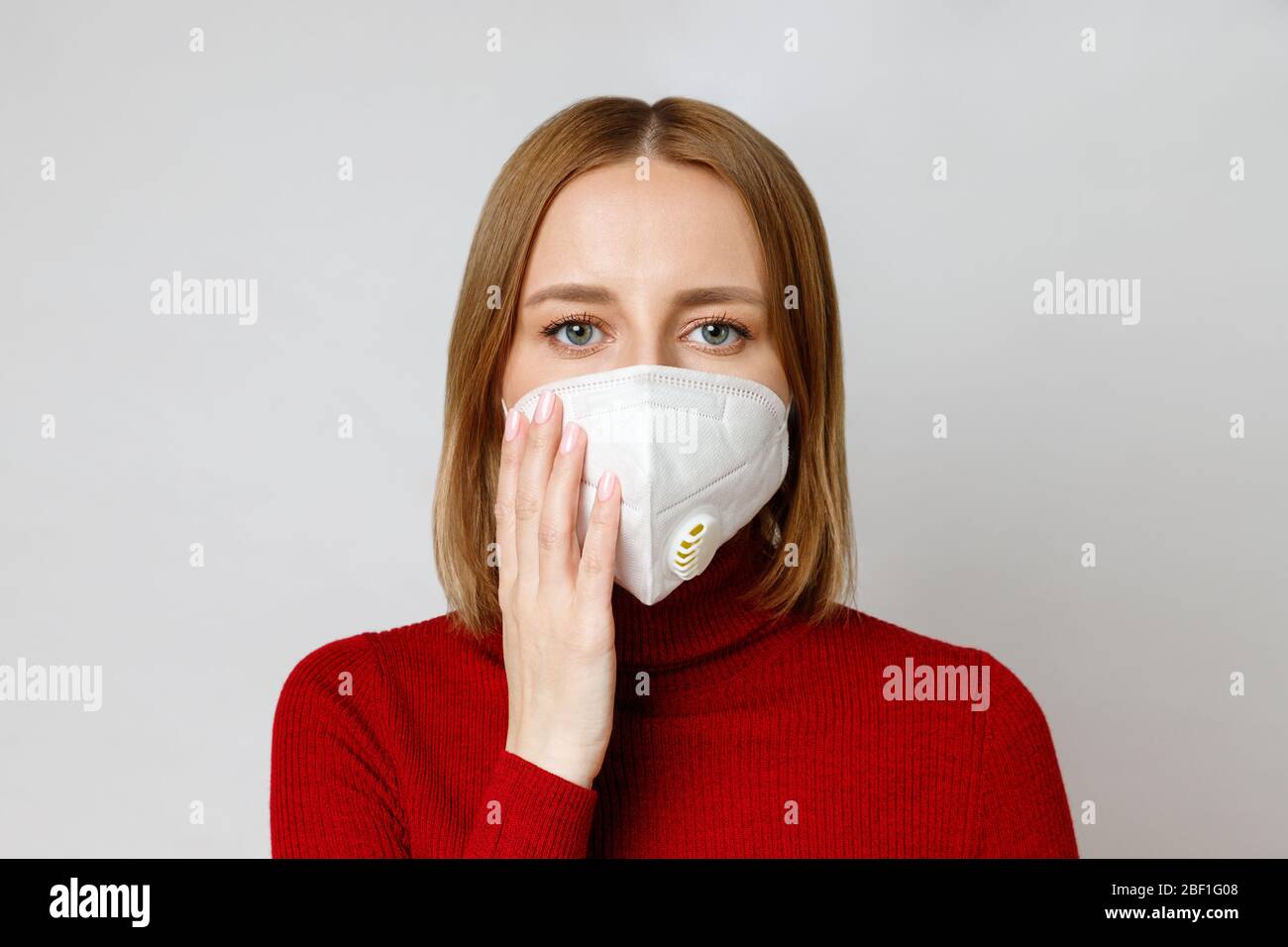 Studio ritratto di donna che indossa una maschera facciale, primo piano, isolato su sfondo grigio. Influenza, allergia alla polvere, protezione contro il virus, coronaviru Foto Stock