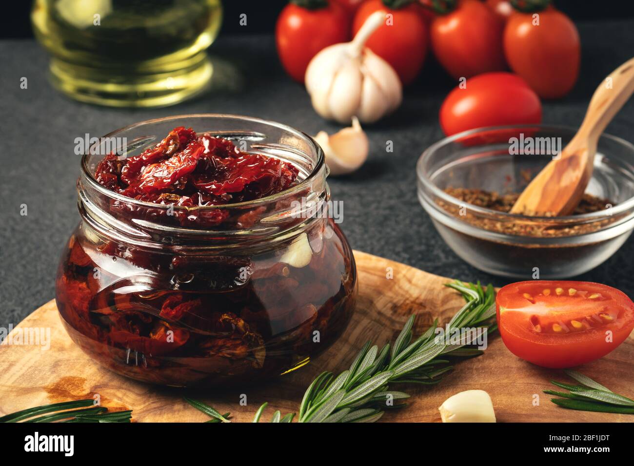 Cuocere i pomodori secchi in un vaso di vetro con olio d'oliva, aglio e rosmarino. Foto Stock