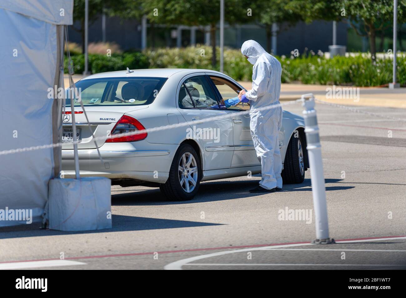 Sugar Land, Texas - 16 aprile 2020: Vestito con completo equipaggiamento protettivo un operatore sanitario raccoglie informazioni da anziani coppia seduta all'interno del loro Foto Stock