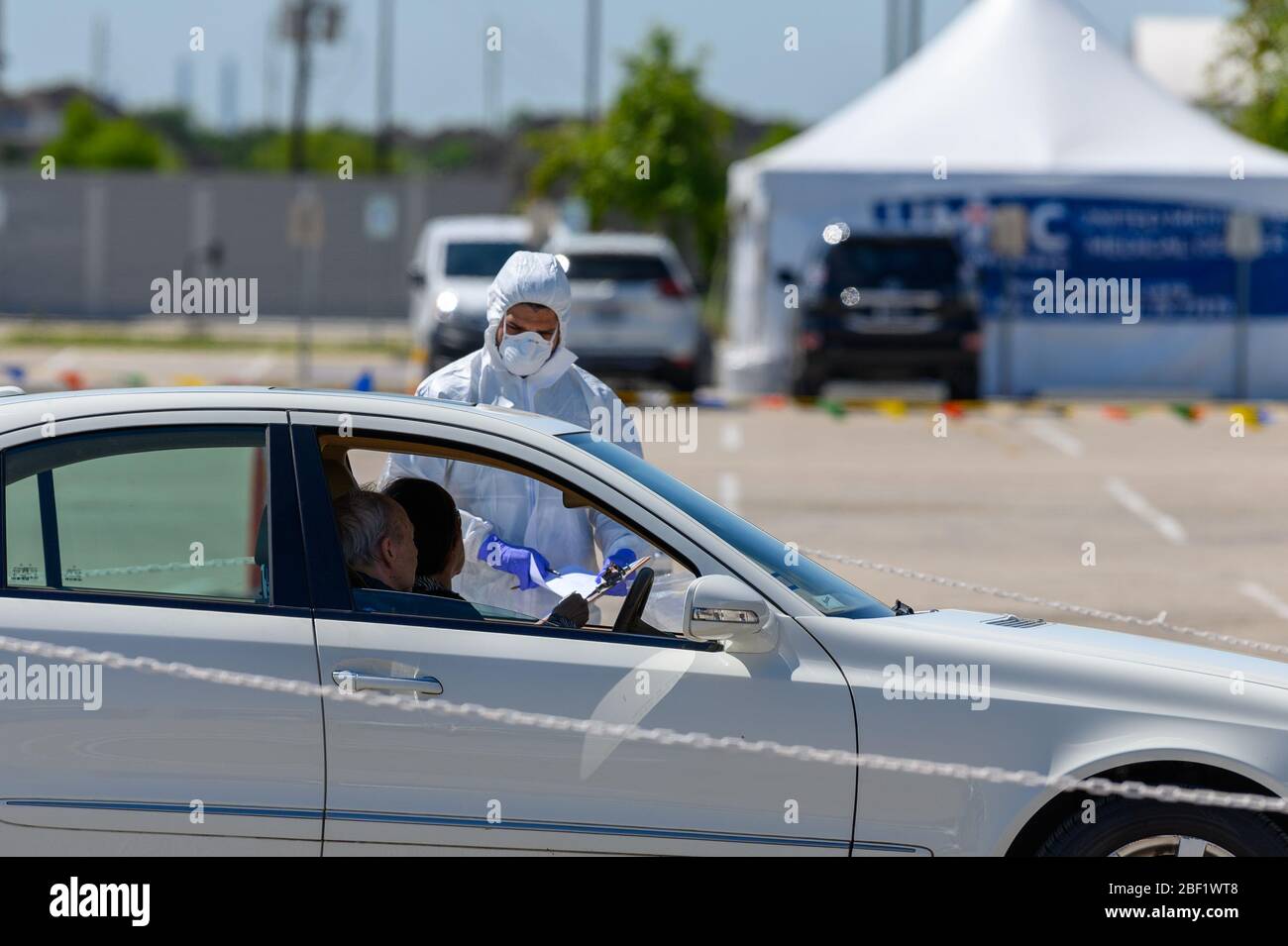 Sugar Land, Texas - 16 aprile 2020: Vestito con completo equipaggiamento protettivo un operatore sanitario raccoglie informazioni da anziani coppia seduta all'interno del loro Foto Stock