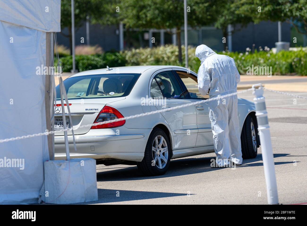 Sugar Land, Texas - 16 aprile 2020: Vestito con completo equipaggiamento protettivo un operatore sanitario raccoglie informazioni da anziani coppia seduta all'interno del loro Foto Stock