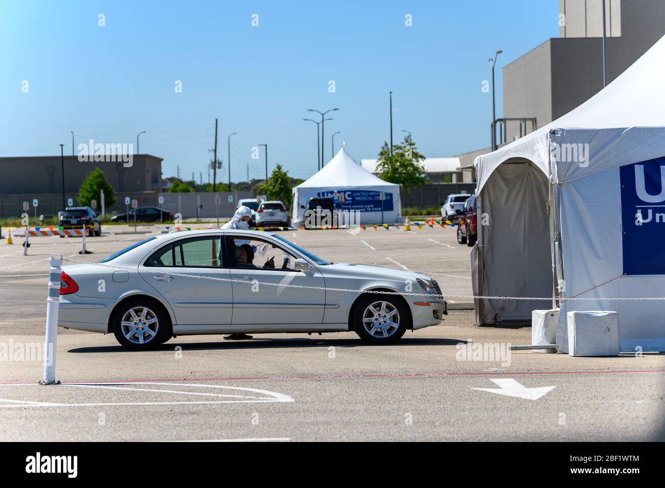 Sugar Land, Texas - 16 aprile 2020: Vestito con completo equipaggiamento protettivo un operatore sanitario raccoglie informazioni da anziani coppia seduta all'interno del loro Foto Stock