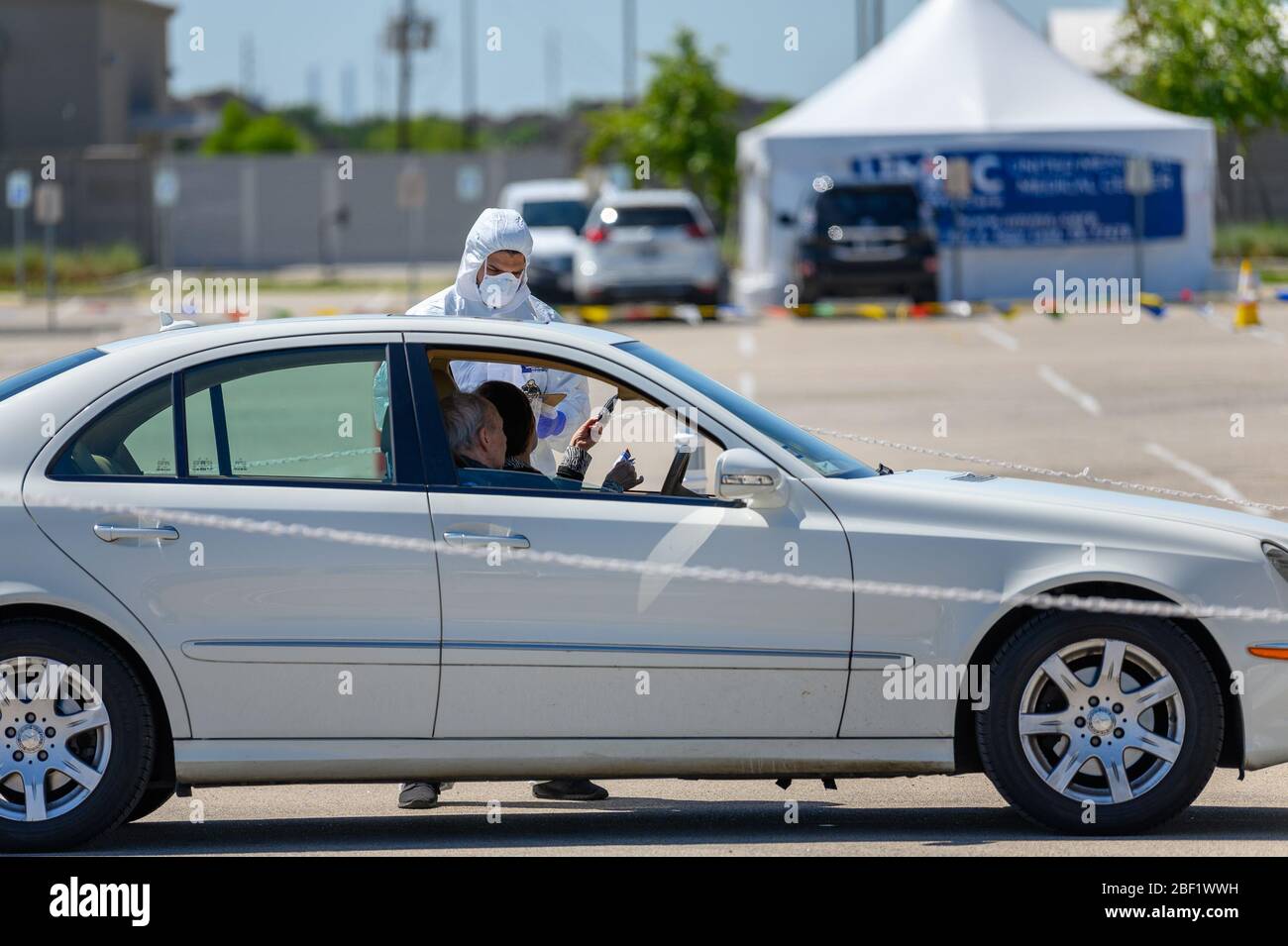 Sugar Land, Texas - 16 aprile 2020: Vestito con completo equipaggiamento protettivo un operatore sanitario raccoglie informazioni da anziani coppia seduta all'interno del loro Foto Stock