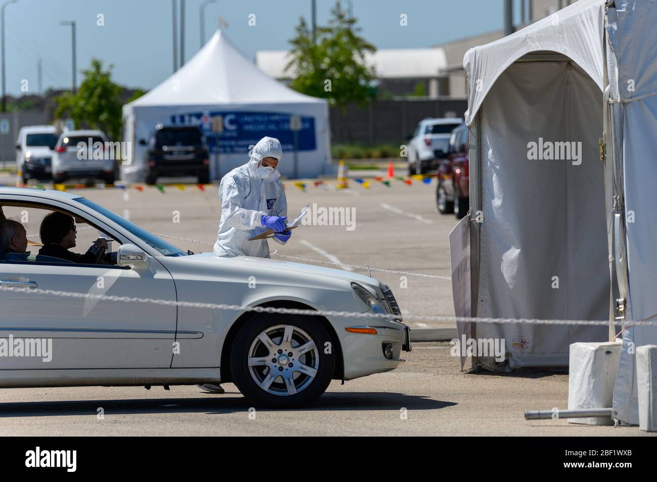 Sugar Land, Texas - 16 aprile 2020: Vestito con completo equipaggiamento protettivo un operatore sanitario raccoglie informazioni da anziani coppia seduta all'interno del loro Foto Stock