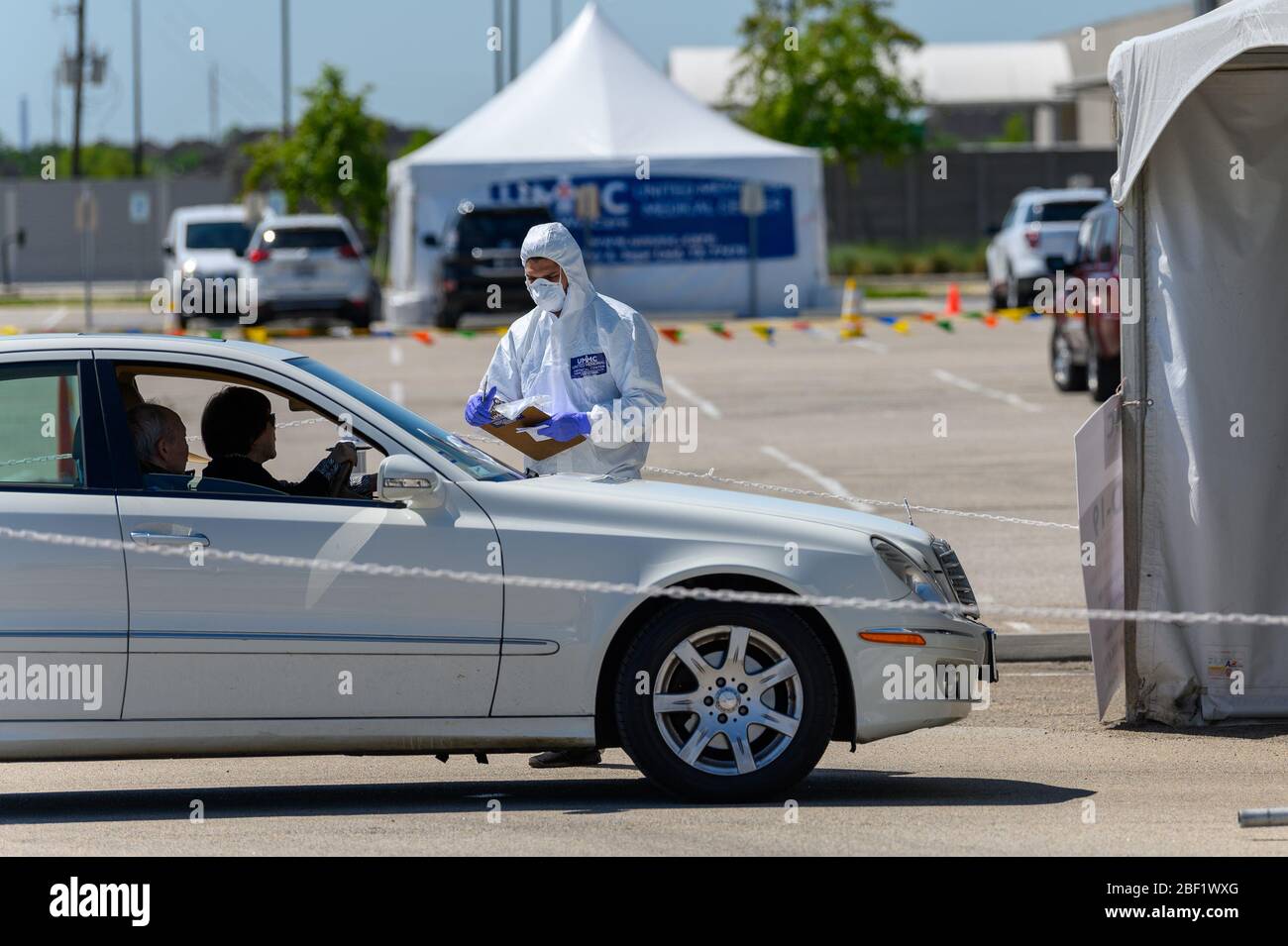 Sugar Land, Texas - 16 aprile 2020: Vestito con completo equipaggiamento protettivo un operatore sanitario raccoglie informazioni da anziani coppia seduta all'interno del loro Foto Stock