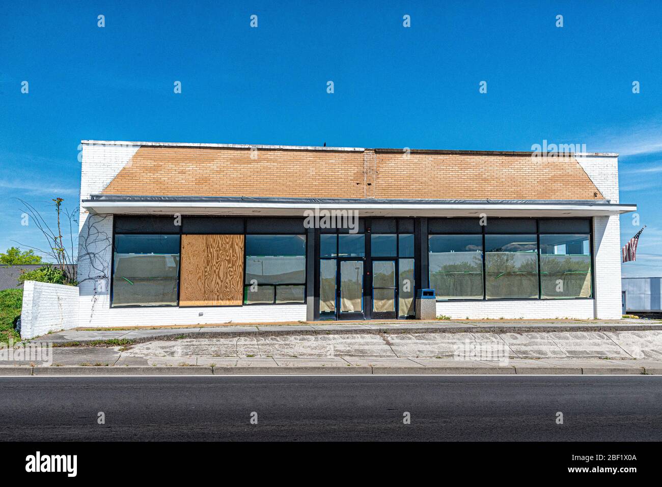 Colpo orizzontale di un fallimento di un business con una vecchia bandiera americana sbiadita sotto un cielo blu. Foto Stock