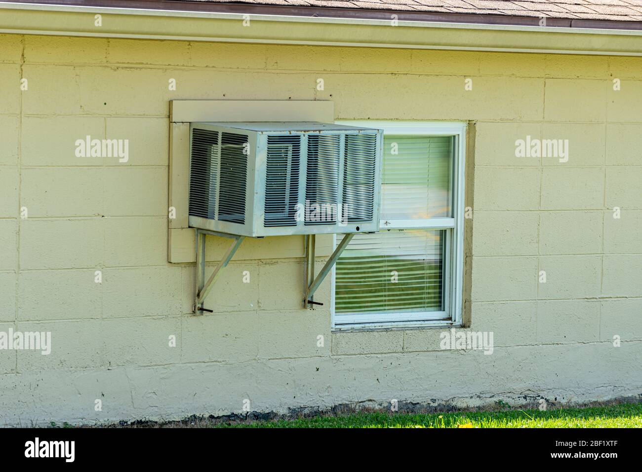 Colpo orizzontale di un condizionatore d'aria di finestra montato sulla parete con un coperchio su di esso dall'esterno. Foto Stock
