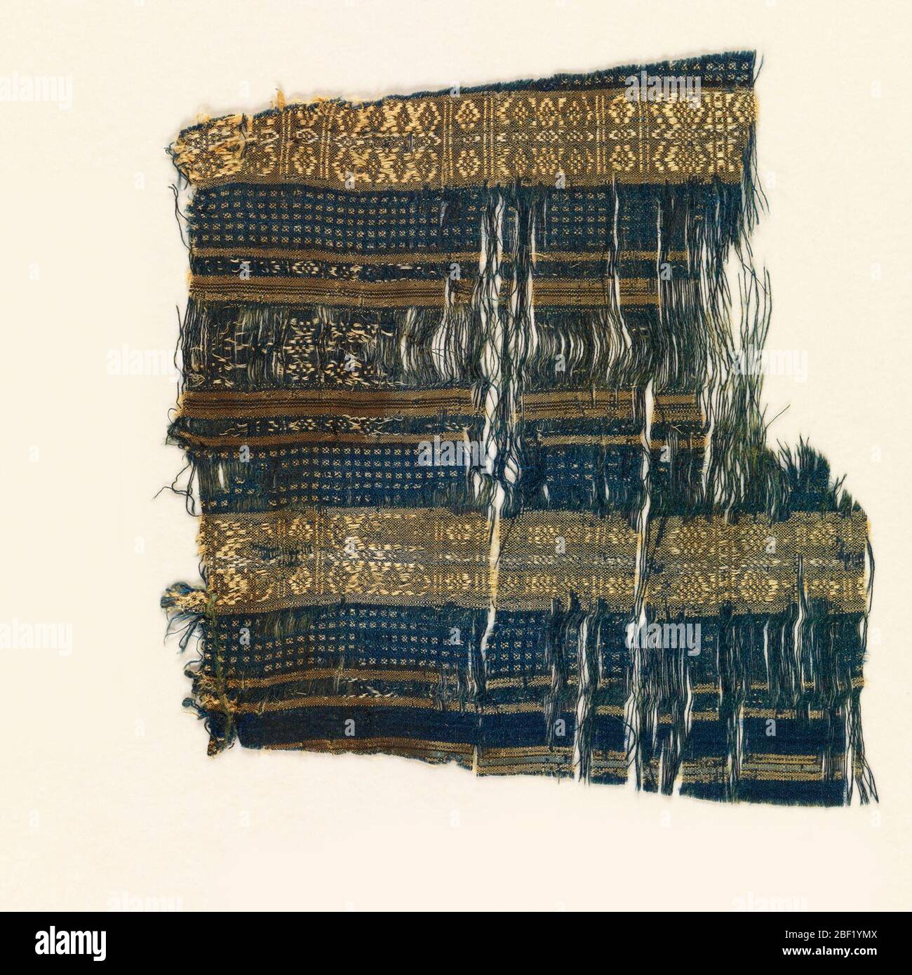 Frammento. Frammento di un indumento in seta blu con strisce strette e larghe in tan con minuscole figure geometriche. Foto Stock