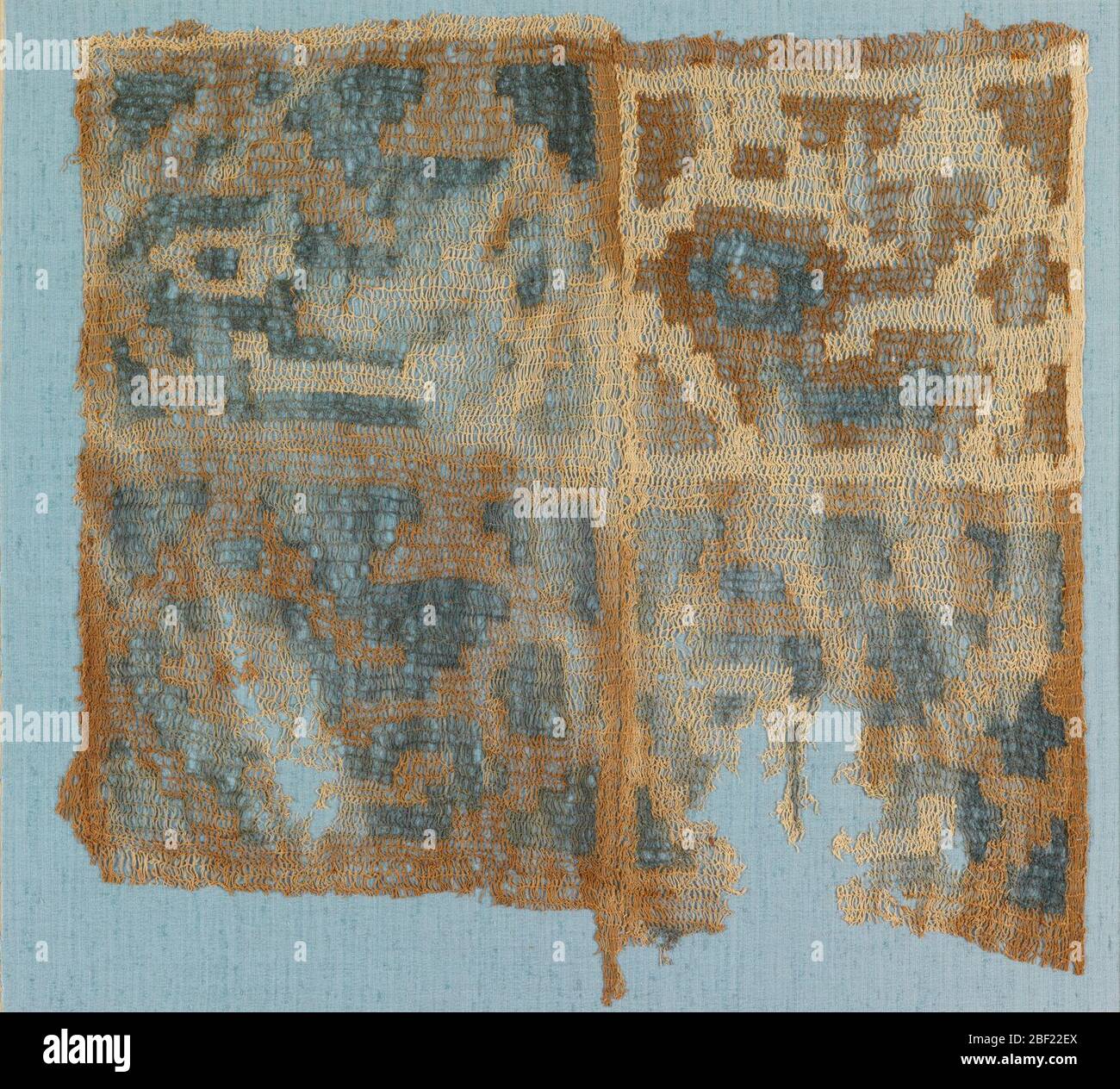 Frammento. Pannello quadrato composto da due pezzi cuciti insieme. Il pannello è diviso in quattro quadrati con una sola ripetizione di un grande uccello stilizzato con elaborato topknot e piccole forme geometriche di riempimento in ciascuno. In combinazione di cotone blu, marrone e naturale. Foto Stock