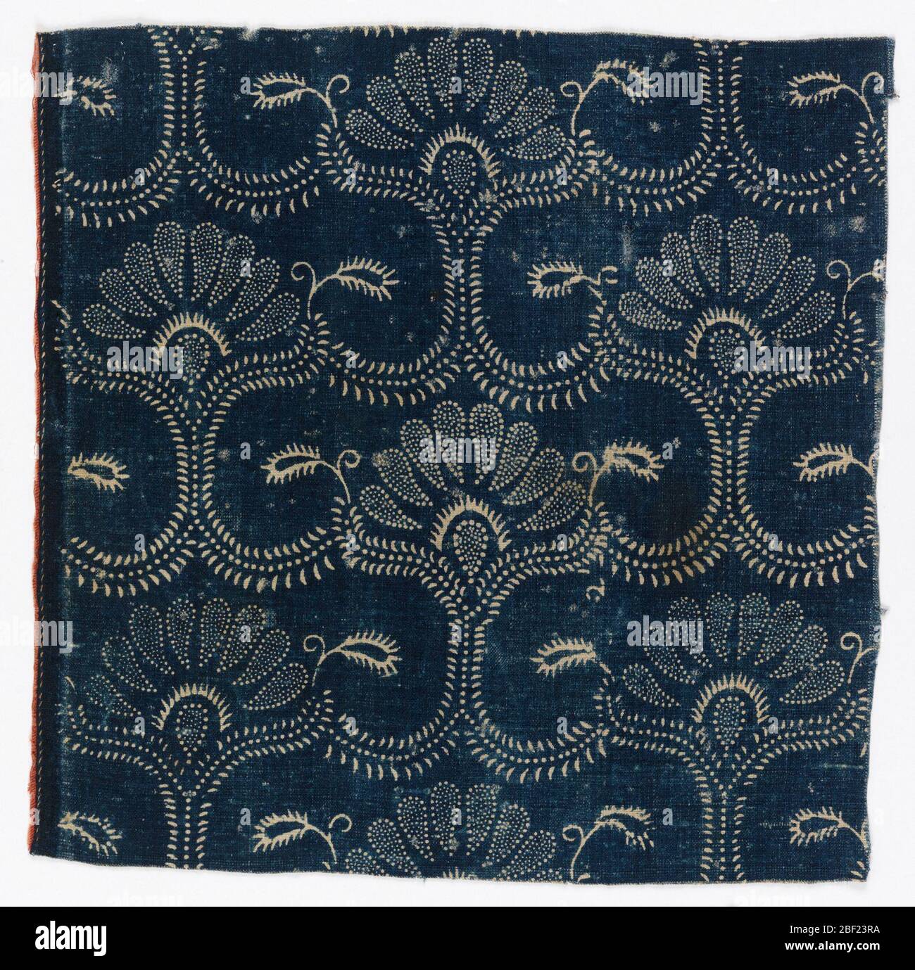 Tessile. Tessuto con motivo blu resist su avorio che mostra forme floreali, una sopra l'altra, in un modello a mezza goccia. Bocchetta su un lato. Stretta striscia rossa di tessuto cucita sulla cimossa. Foto Stock