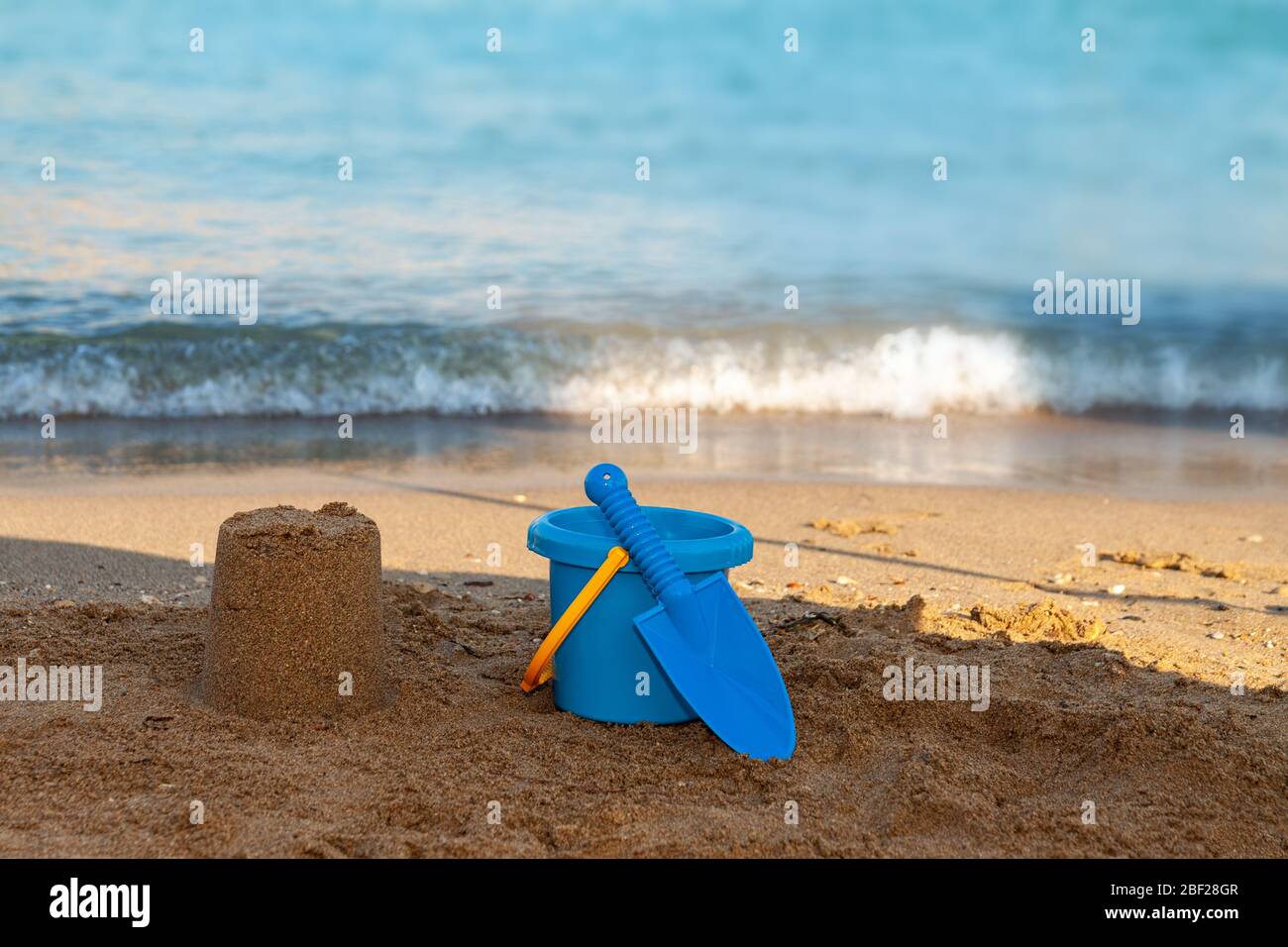 Una persona seduta su una spiaggia di sabbia accanto all'oceano Foto Stock
