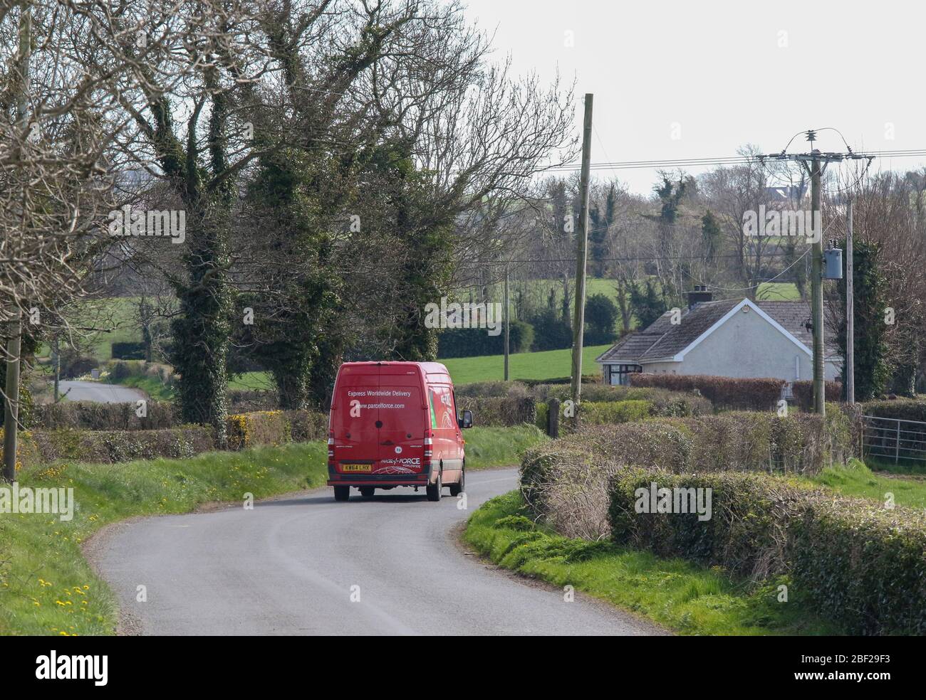 Retro di Royal Mail Parcelforce pulmino di transito rosso che viaggia lungo la strada rurale in Irlanda del Nord facendo la consegna dei pacchi durante il blocco aprile 20 Foto Stock