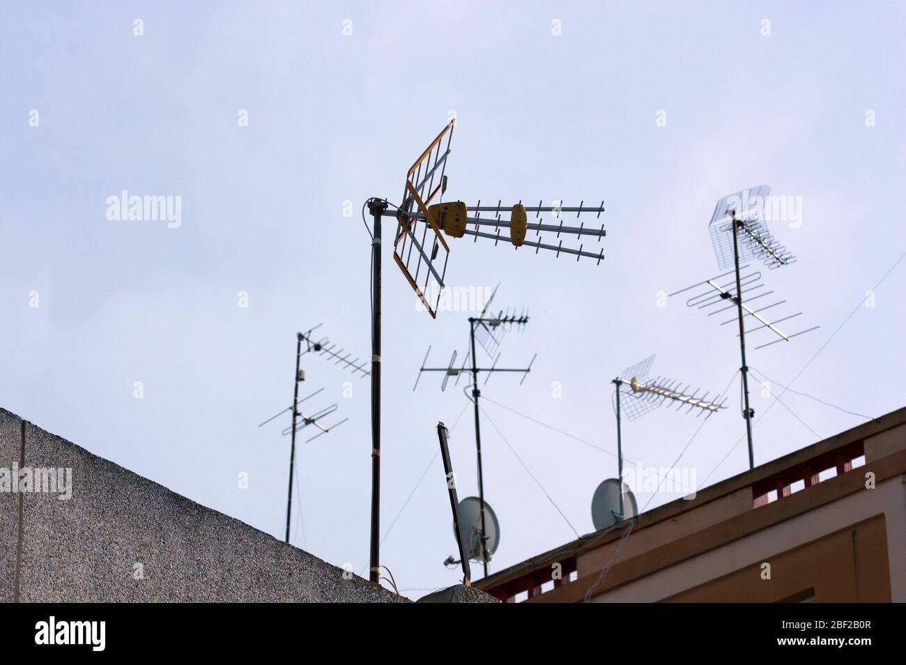 Alcune antenne della televisione digitale terrestre (DTT), insieme a quelle più vecchie e alcune antenne satellitari, sui tetti degli edifici con spazio per testi in Foto Stock