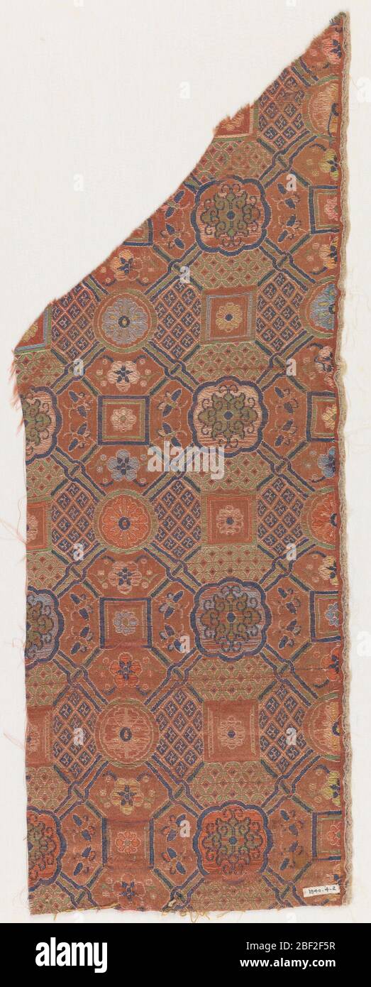 Rifinitura. Terra rosso-arancio scuro con un disegno formato da trama blu scuro primaria e trame secondarie di blu chiaro e scuro, verde, rosa, marrone chiaro e giallo. Disegno geometrico con losanghe e swastikas minuti raggruppati in quadrati con rosette in alcune aree del disegno. Foto Stock