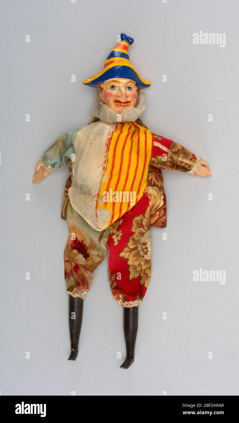 Punzone. Testa dipinta con colori vivaci in un alto cappello bicorno a  righe. Stivali neri. Suite fiorita con mezzo bianco e mezzo gilet a  strisce. Guance rosate e denti esposti Foto stock -