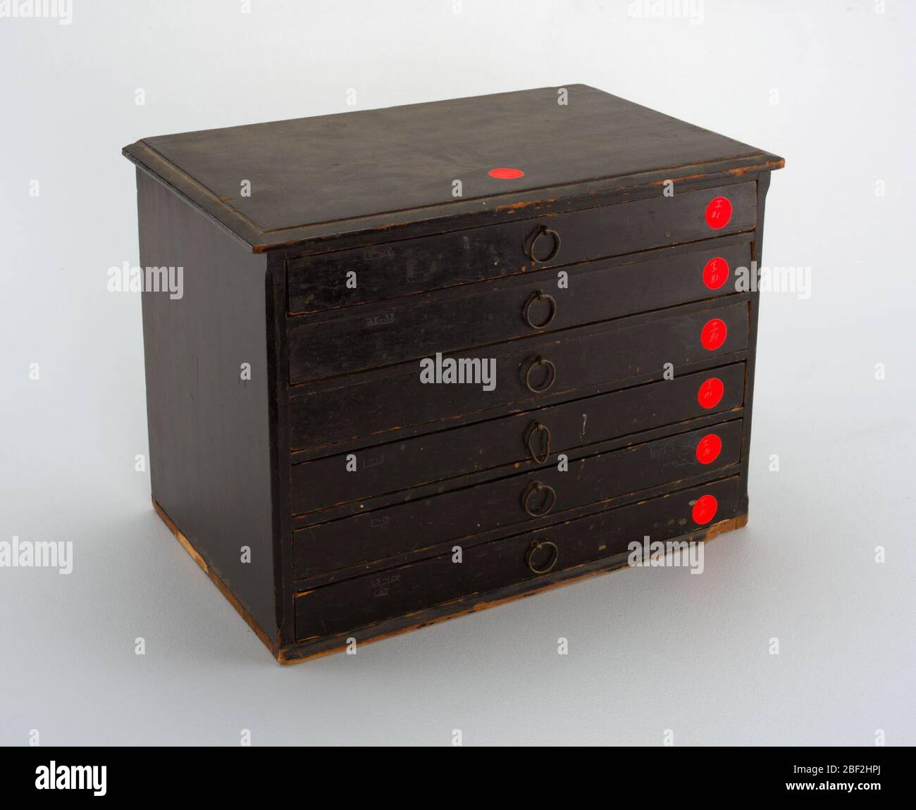 150 impronte di tenuta in gesso. Cassettiera in miniatura, rettangolare, con angoli smussati, sagomatura sul fondo, sulla parte superiore. Un anello di filo al centro di ciascun cassetto rivestito in velluto. Foto Stock