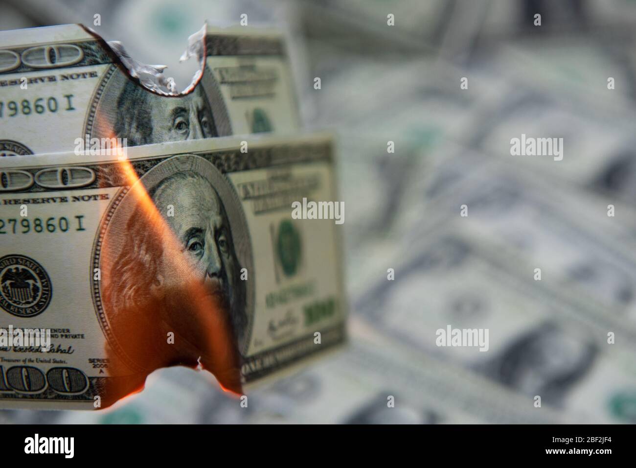 Bruciare cento dollari come simbolo di recessione economica. Foto Stock