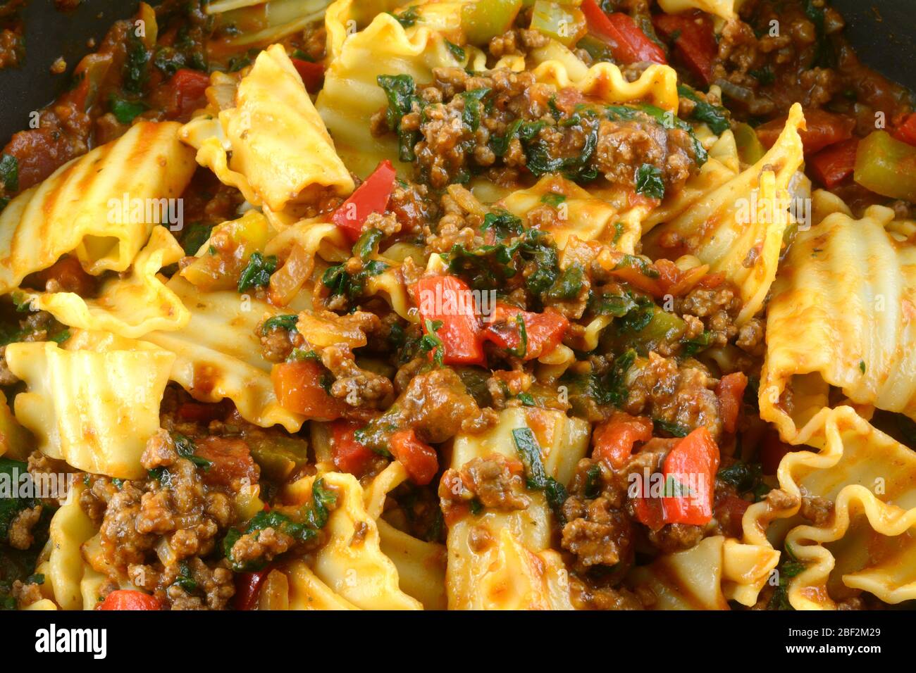 Primo piano di casseruola di lasagne con carne di hamburger, spinaci, peperoni rossi, peperoni verdi e cipolle Foto Stock