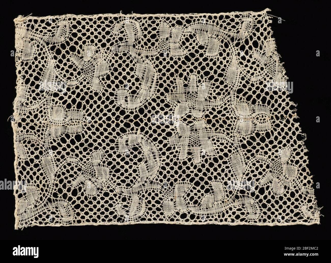 Frammento. Frammento stile binche con un disegno di bordo di rami fioriti che si incurvano verso l'alto e indietro dal bordo del pezzo. Terra trio Cinq. Disegno ripetuto in senso inverso nella metà superiore del pezzo. Fragment è composto da due pezzi cuciti insieme al centro. Foto Stock