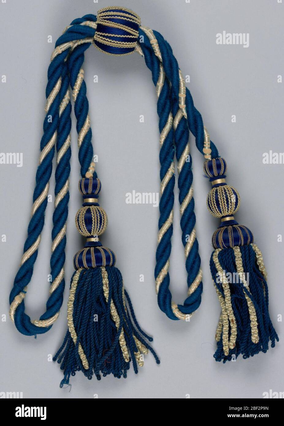 Riparte posteriore con un taseled. Cravatta con dorso in castone di fili blu e bianchi ritorti; ogni estremità termina con una grande nappina blu. Il centro del controstorno ripiegato è bloccato da un cordone di scivolamento grande. Foto Stock