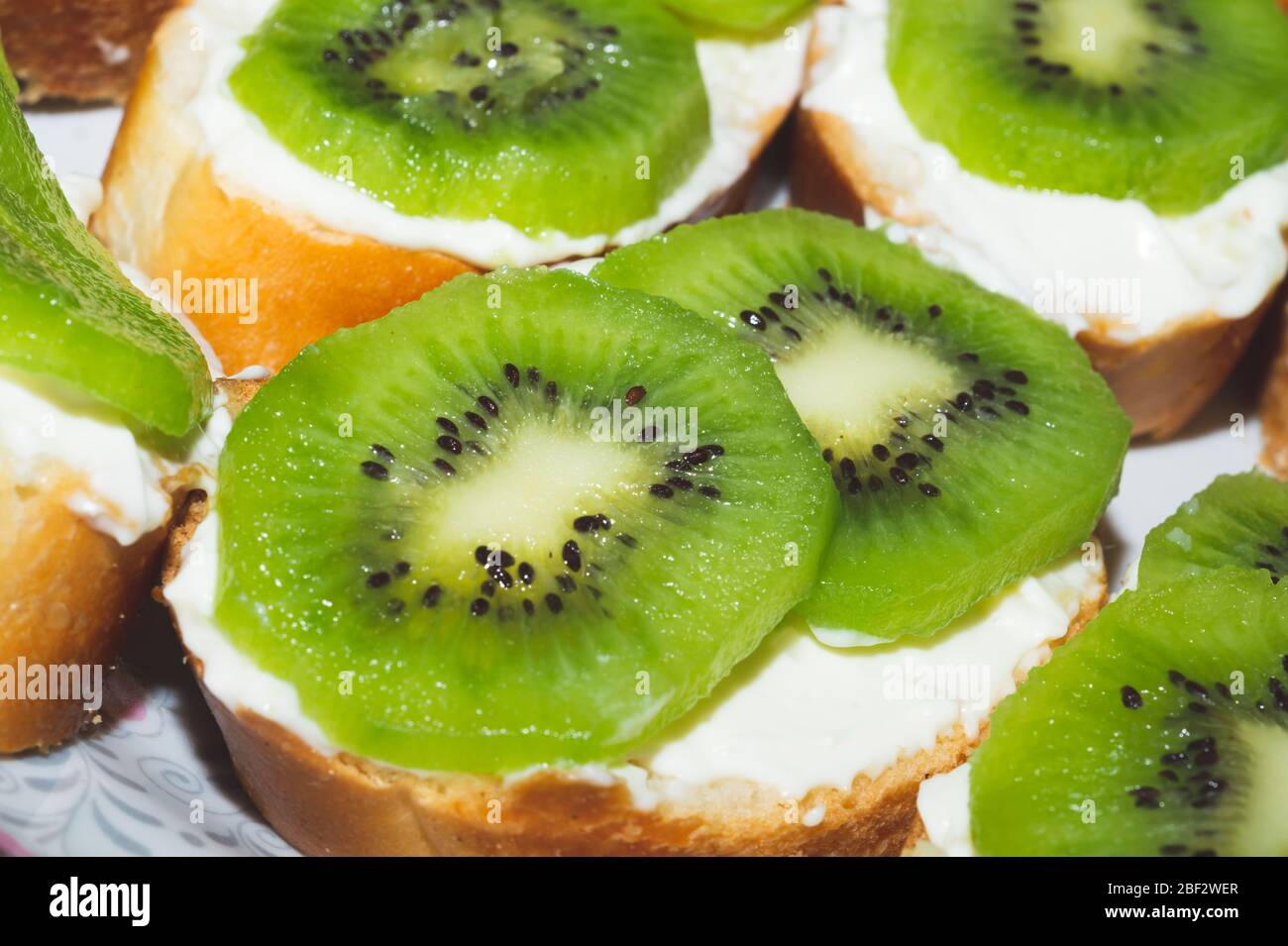 Panini con kiwi, pane con fette di frutta, fondo con antipasto Foto Stock