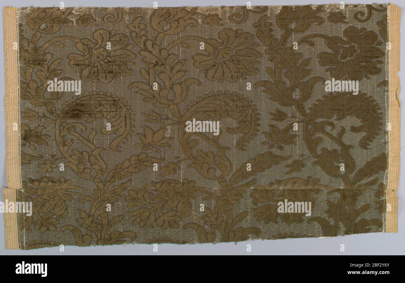 Frammento. Selvage a larghezza di selvage con un disegno di colore marrone scuro che scorre foglie e fiori rivolti in direzioni alternate. Foto Stock