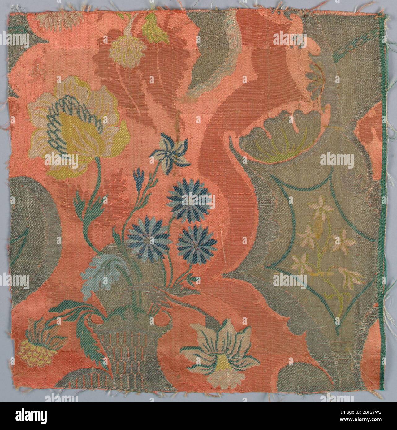 Frammento. Frammento di damask di seta broccata in stile ‘bizzarro’. Rosa, rosso e argento con dettagli broccati nelle sfumature del blu che mostrano un cesto di fiori e forme fantastiche. Foto Stock